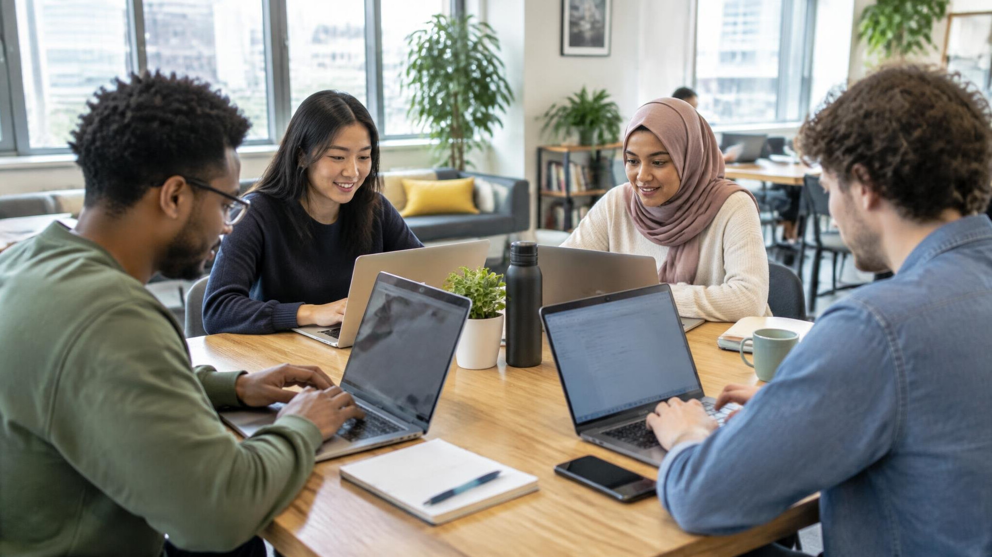 Small group of people working on laptops around a table